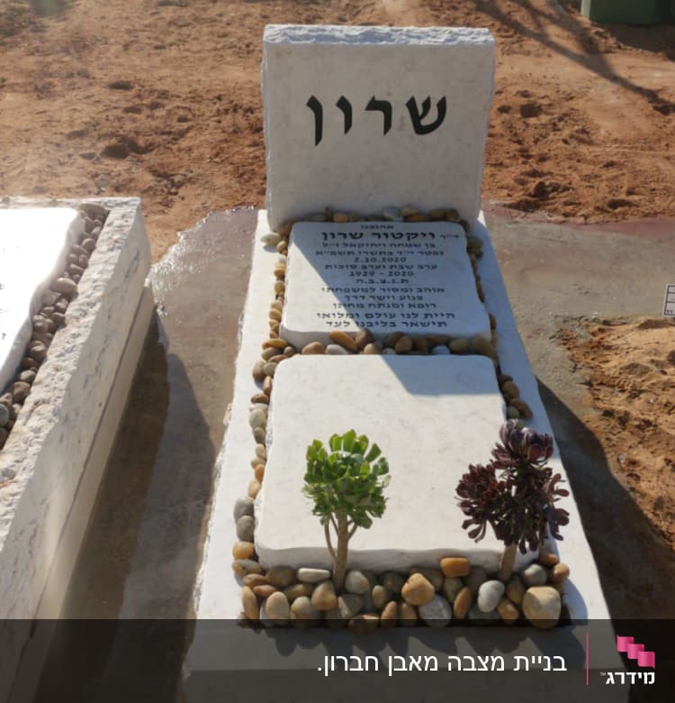 מצבה עם כיתוב בעברית ואבנים מסביב